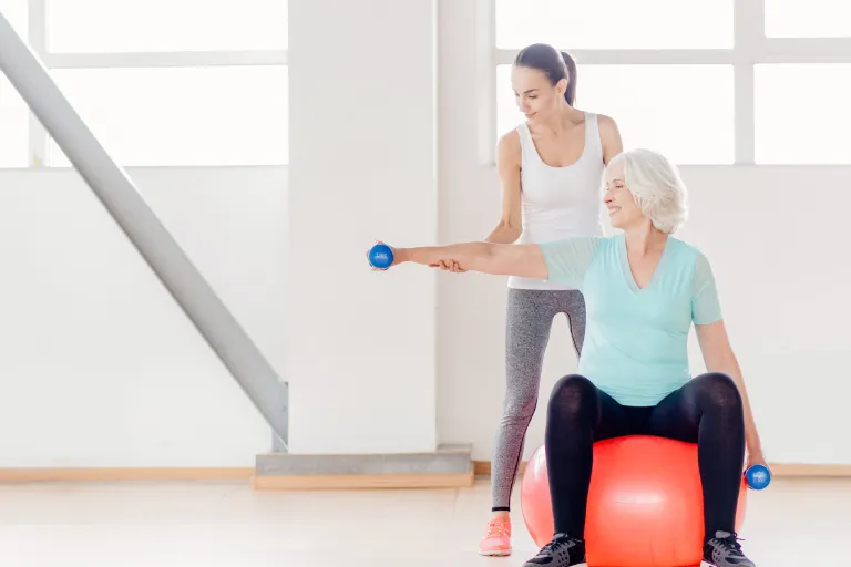 Strengthening Programs Services Cheerful elderly woman sitting on the fitness ball